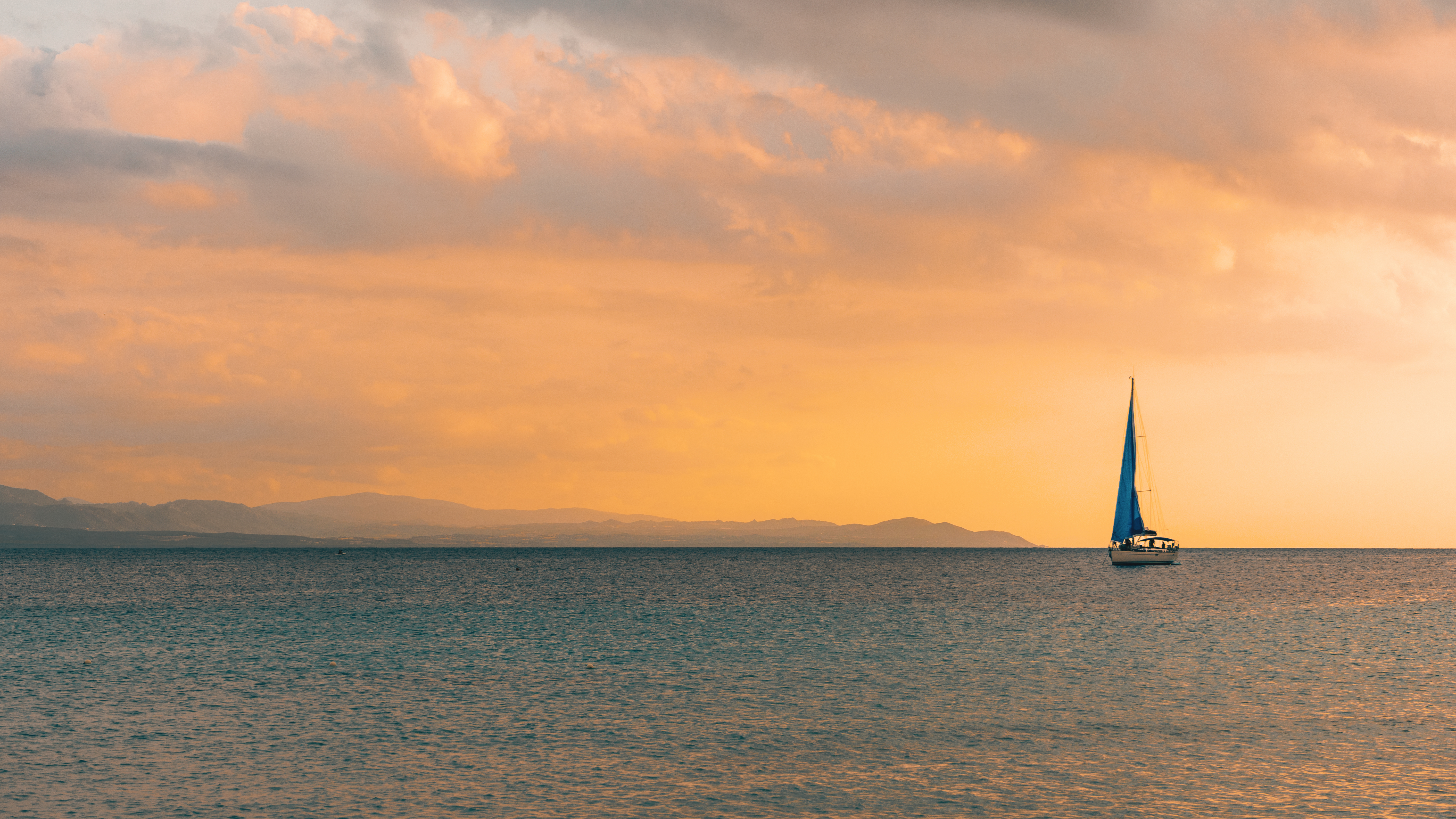 Una barca a vela che naviga sul mare durante un tramonto sereno.